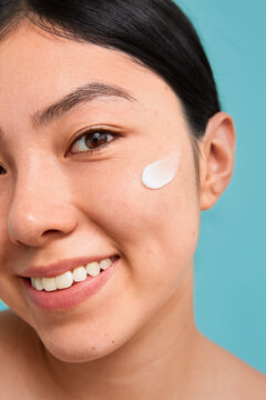 Close-up of a smiling woman with moisturizer on her cheek