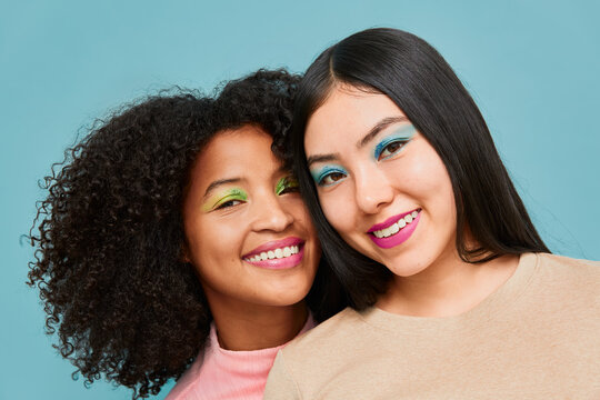Two women smiling with colorful eyeshadow and bright lipstick