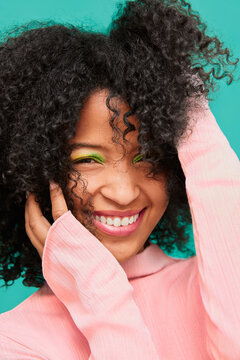 Smiling woman with curly hair and bold green eyeshadow