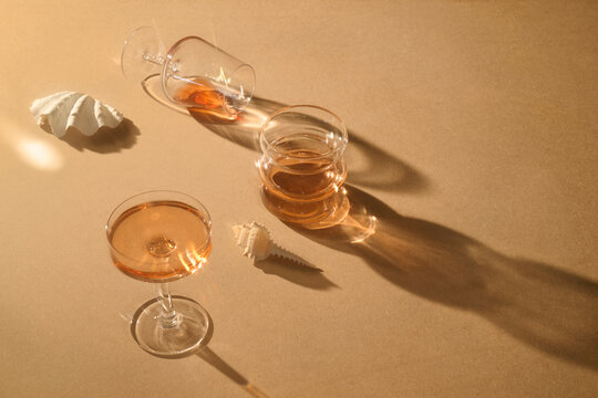 Elegant cocktail glasses with seashell decor on a neutral backround