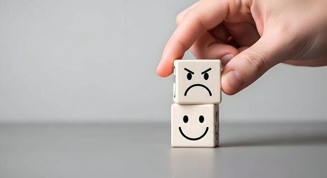 Hand holding two cubes with contrasting facial expressions, happy and angry emotion feeling