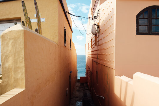 Narrow alleyway leading to blue ocean view