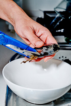 a man cleaning a mussel with scissors at home