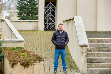 Man stands calmly on paved walkway beside steps © Iurii Gagarin
