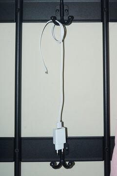 Charging cable hanging on wall hooks in a room