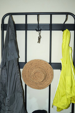 Clothing, a hat, and keys hang on hooks by a rack in a home setting
