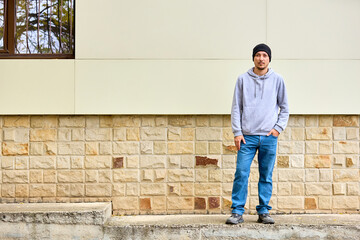 Young man stands casually against stone wall © Iurii Gagarin