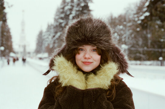 Smiling woman in fur hat and mittens during winter  
