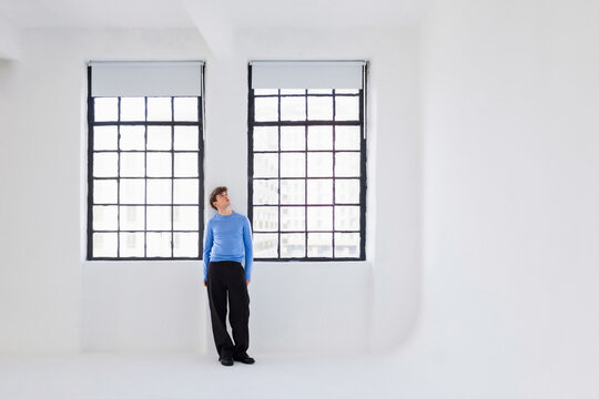 Man In Blue Shirt Standing In Bright White Studio