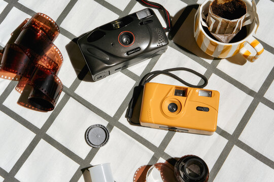 Old Cameras and Film Rolls on a Table With a Coffee Cup