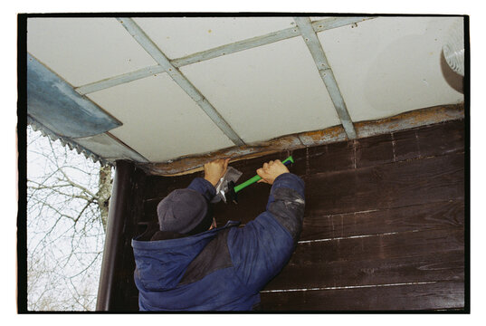 A man is repairing the ceiling on the veranda.