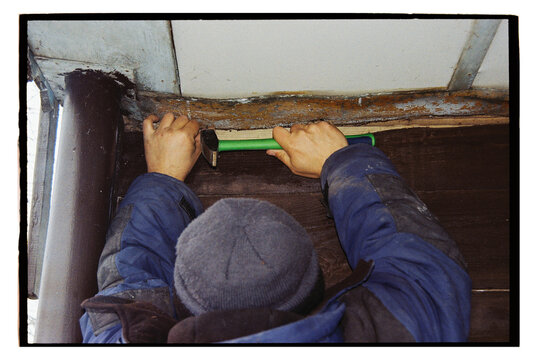 A man is repairing the ceiling on the veranda.