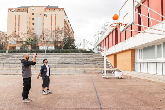 Videographer filming basketball shot going through hoop