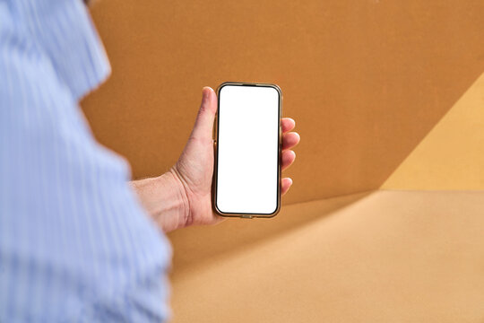 Hand Holding Phone With Blank Screen Against Brown Background