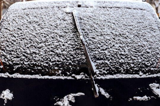 Snow-covered rear window of a car with wipers.