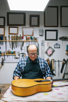 Luthier craftsman carefully making a classical guitar in workshop