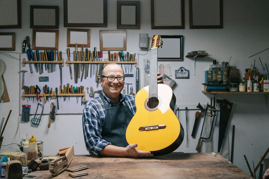 Luthier displaying acoustic guitar in professional workshop