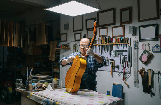 Luthier crafting classical guitar in his workshop