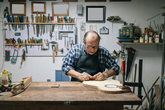 Luthier crafting classical guitar in his workshop