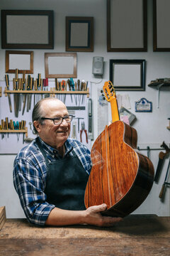 Luthier holding classic guitar in workshop