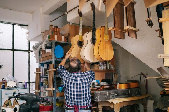 Luthier crafting acoustic guitars in workshop