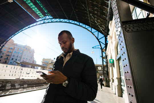 Man using phone at a train station platform