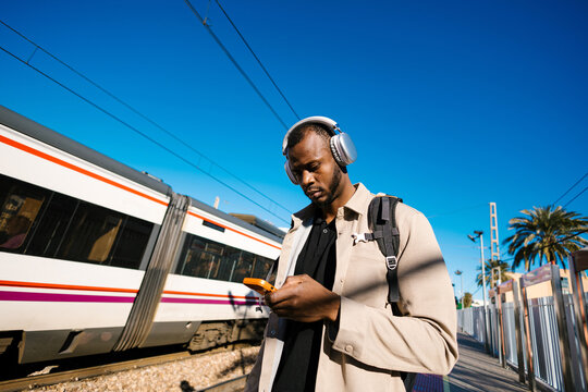 Young man commuting with smartphone and headphones at station