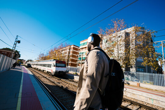 Man with headphones waiting for train at station