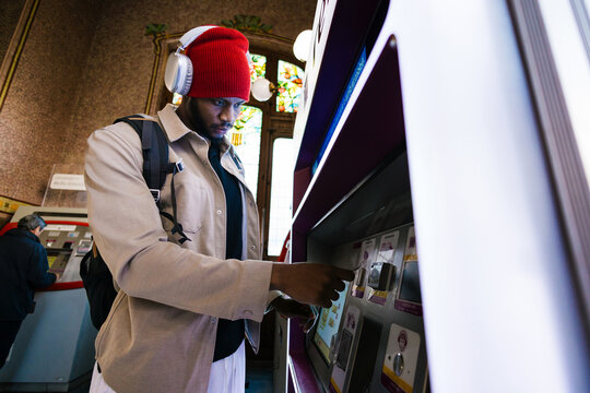 Traveler wearing headphones using ticket vending machine