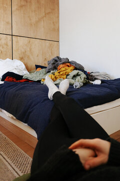 Person relaxing on bed with unorganized clothes