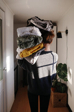 Woman carrying large stack of clean laundry