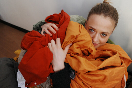 Woman smiling holding large pile of colorful laundry