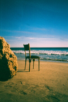 a simple chair by the shore with waves and sky, 35mm film