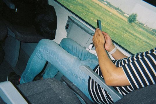a man charges his phone by the window during a train trip, 35mm film