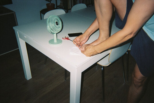 a man trimming his toenails at a home table, 35mm film