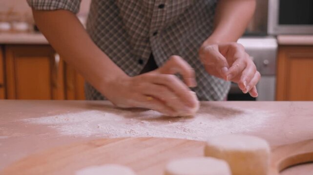 Bakery workers preparing pastry surfaces. Kitchen scene of bakers shaping and dusting bread dough. People working together to form dough and coat with flour in cozy bakery environment
