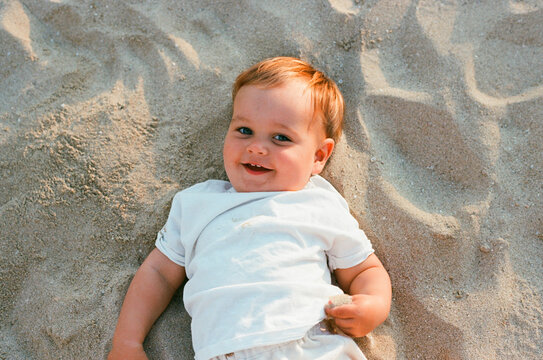 Portrait of a Smiling Baby on a Sandy Beach Film Photo