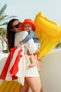 woman holding a child by a yellow inflatable float  Summer Travel 