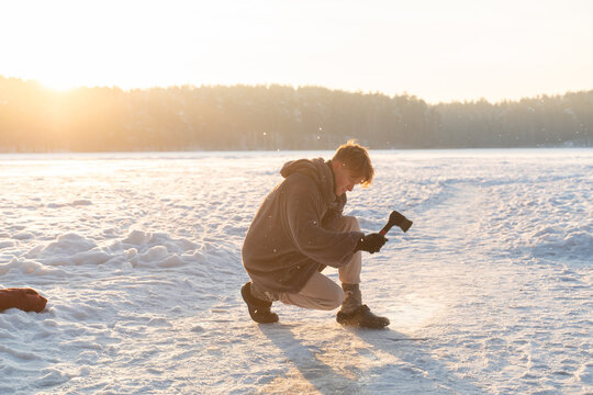 Man Cuts Ice Hole In The Lake At Winter