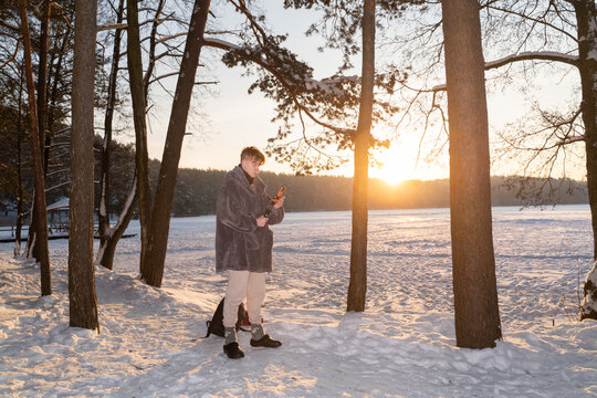 Man Using Phone On Tripod At Frozen Lake at Sunrise