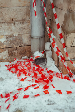 Red and white tape on the ground near a drain in winter