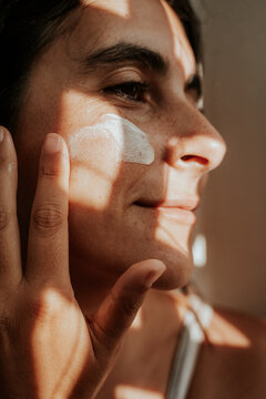 Woman applying face cream in natural light 