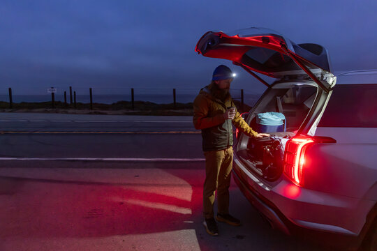 Man packing Luggage into car at night 