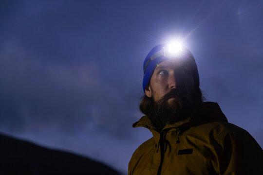 Portrait of hiker with headlamp in dark look away 