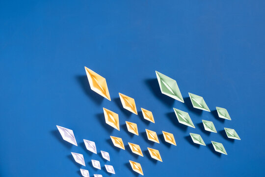 Origami paper boats in different colors sailing on a blue background