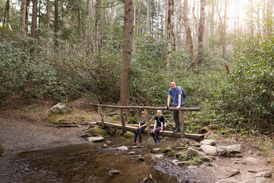 Father and daughters on a hiking bridge across a small stream
