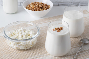Kefir, buttermilk or yogurt, cottage cheese with granola. Yogurt in glass on white wooden background. Probiotic cold fermented dairy drink. Gut health, fermented products, healthy gut flora concept