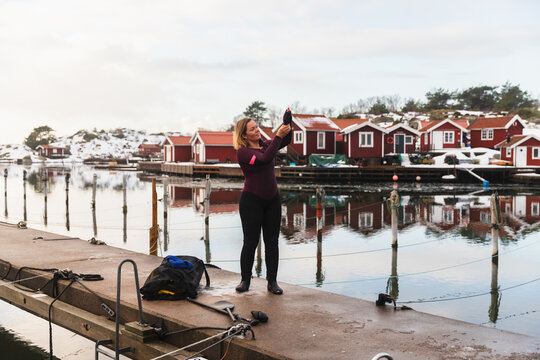 Woman Putting on Full Body Wetsuit for Winter Water Sports