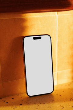 Smartphone mockup leaning on tile wall in sunlight