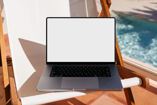 Laptop mockup with white screen at hotel poolside during summer travel